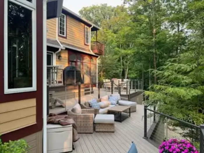 Wood deck with outdoor seating and cable railing behind a two-story home
